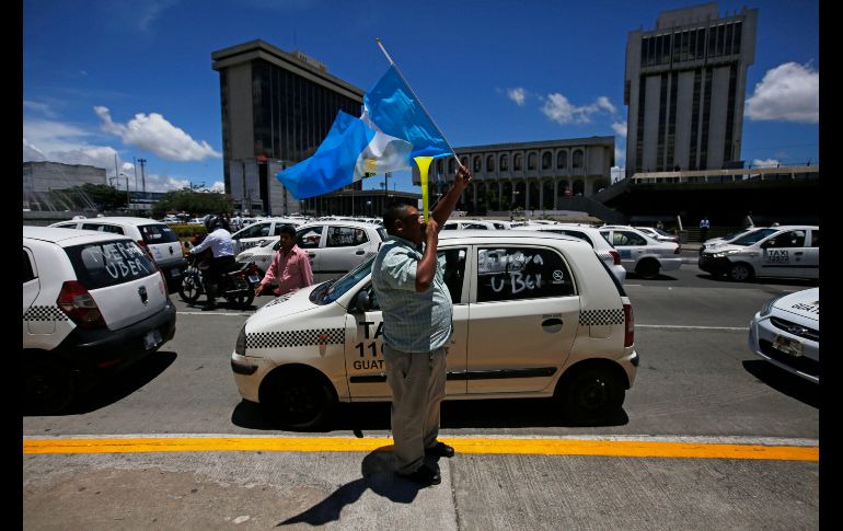 Un taxista agita una bandera de Guatemala frente a la Municipalidad de la Ciudad de Guatemala. Centenares de taxistas bloquearon hoy diferentes rutas de esta capital para protestar contra la plataforma de transporte Uber, a la que le exigen cumplir con los mismos requisitos legales a los que ellos están obligados. EFE/E. Biba