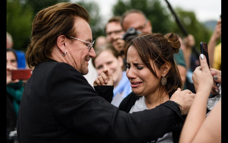 El cantante del grupo U2 y cofundador de la organización no gubernamental ONE, Bono (i), saluda a sus seguidores tras reunirse con la canciller alemana, Angela Merkel, en Berlín. EFE/ C. Bilan