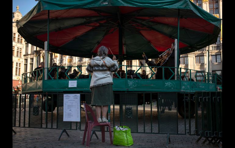 Una mujer en una silla simula estar conduciendo la orquesta que toca en la Gran Plaza de Bruselas, Bélgica. AP/F. Seco