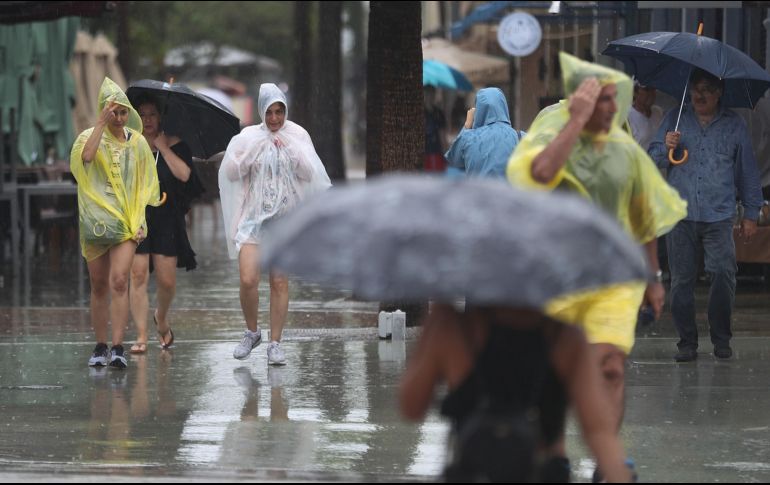 Habitantes intentan caminar en medio de fuertes lluvias. AFP/J. Raedle