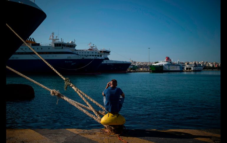 Un hombre se sienta frente a ferris atracados en el puerto griego de El Piero, durante una huelga de personal de ferris que suma dos días. AFP/A. Tzortzinis