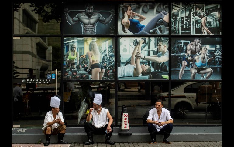 Chefs toman un descanso frente a un gimnasio en Shanghái, China. AFP/J. Eisele