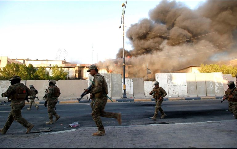 Soldados iraquíes corren mientras emergen columnas de humo de un edificio en Basora. EFE/H. Al-Assadee