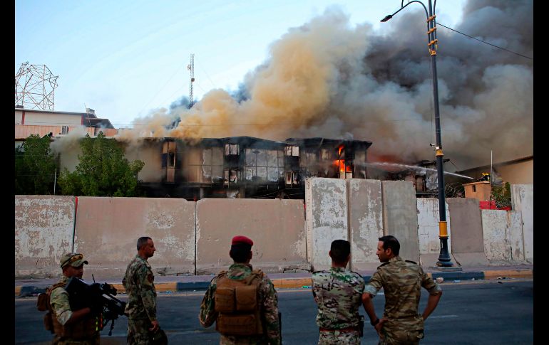 Fuerzas de seguridad observan el incendio en un edificio gubernamental, durante protestas contra el gobierno en Basra, Iraq. AP/N. Al-Jurani