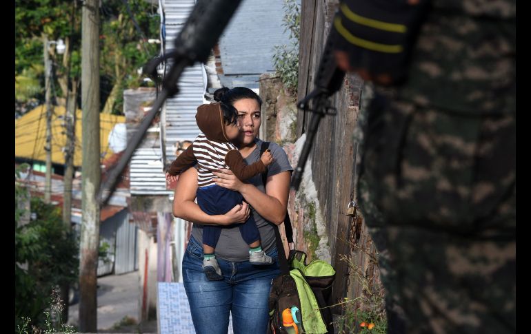 Una mujer con un bebé mira a soldados y policías durante un operativo para hallar a integrantes de una banda criminal en Tegucigalpa, Honduras. AFP/O. Sierra
