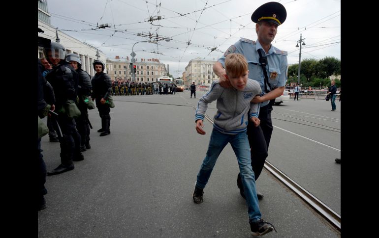 Un policía escolta a un menor en Moscú, Rusia, durante una protesta en contra de una iniciativa de reforma de pensiones que incrementaría la edad de jubilación. AFP/O. Maltseva