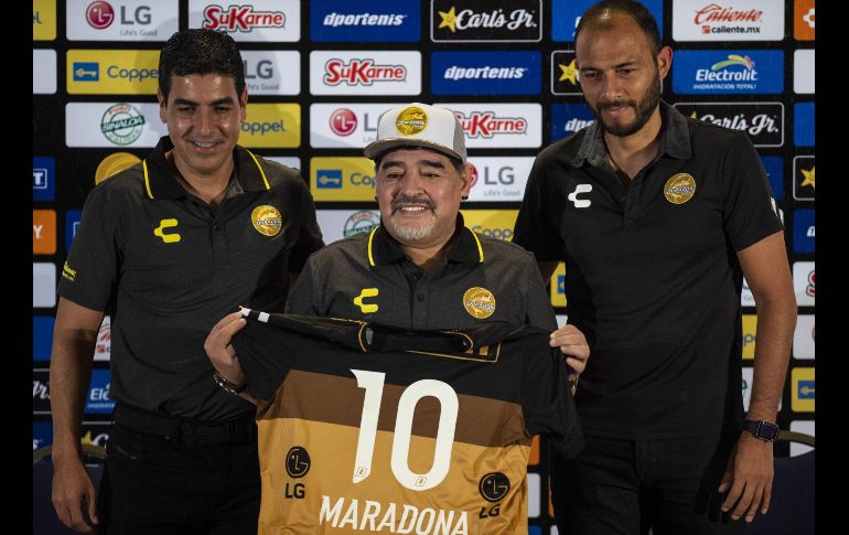 El argentino Diego Armando Maradona (c) muestra una camiseta del equipo Dorados de Culiacán, durante su presentación oficial en el equipo en Culiacán, Sinaloa. AFP/P. Pardo