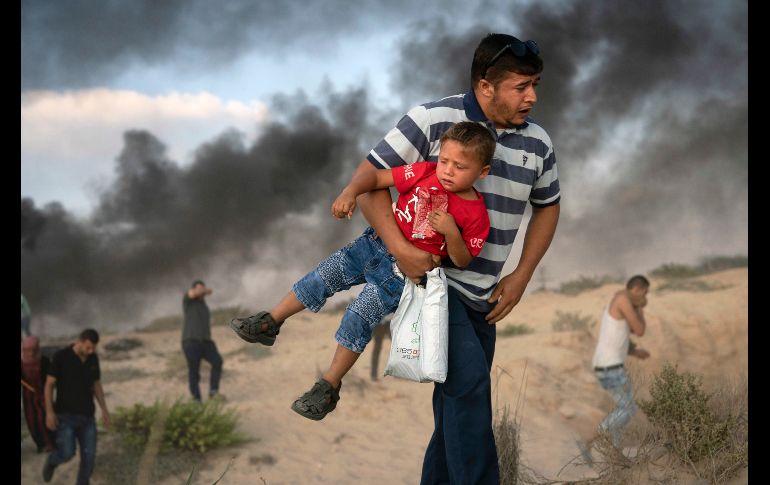 Un palestino con un niño huye del gas lacrimógeno lanzado por soldados israelíes, durante una protesta en Beit Lahiya, en la Franja de Gaza, fronteriza con Israel. AP/F. Dana