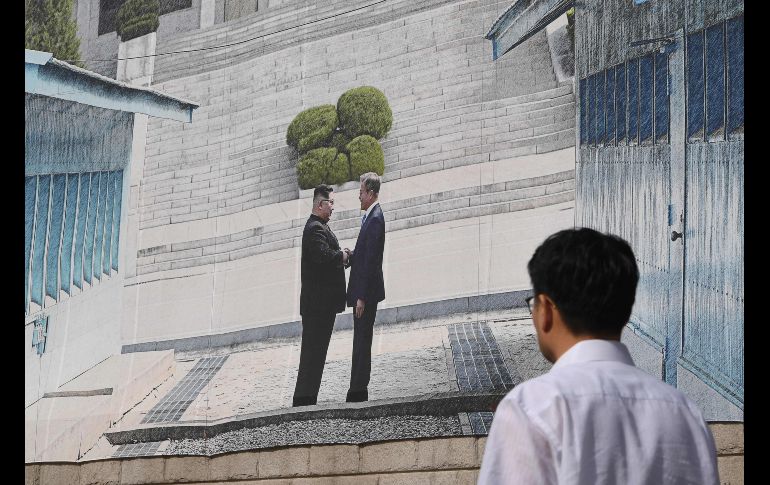 Un hombre pasa junto a un póster que muestra el saludo en la cumbre entre el presidente sudcoreano Moon Jae-in y el líder norcoreano  Kim Jong Un, en Seúl, Corea del Sur. AFP/Jung Yeon-je