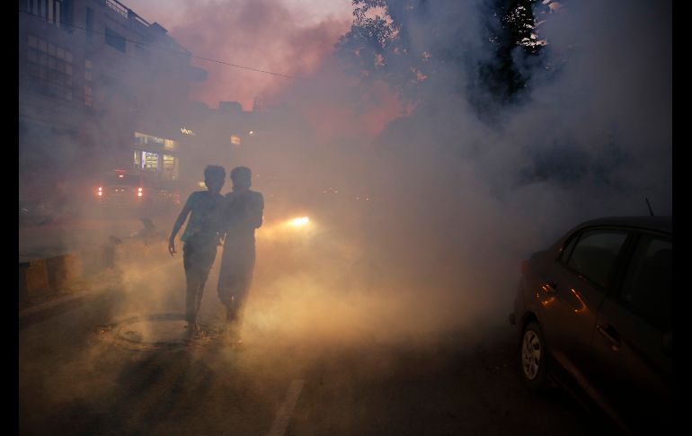 Jóvenes pasan por una nube durante una fumigación en Allahabad, India, para prevenir el crecimiento de mosquitos transmisores de enfermedades, como malaria y encefalitis. AP/R. Kumar