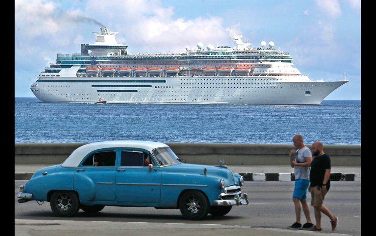 Personas y un automóvil clásico transitan por el el malecón mientras un crucero entra a la bahía de La Habana, Cuba. EFE/Y. Zamora