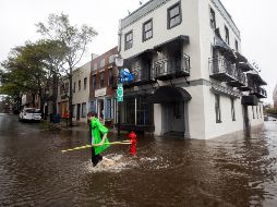 Varios vecinos caminan por una calle inundada tras el paso del huracán 