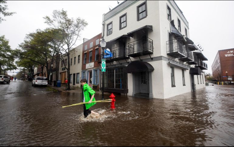 Varios vecinos caminan por una calle inundada tras el paso del huracán 