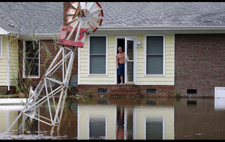 Un hombre se asoma de una casa afectada en Lumberton.