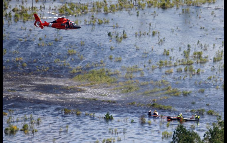 Personal de la Guardia Costera estadounidense en un helicóptero se prepara para levantar a habitantes varados en Burgaw, Carolina del Norte, debido a las inundaciones por el efecto de 
