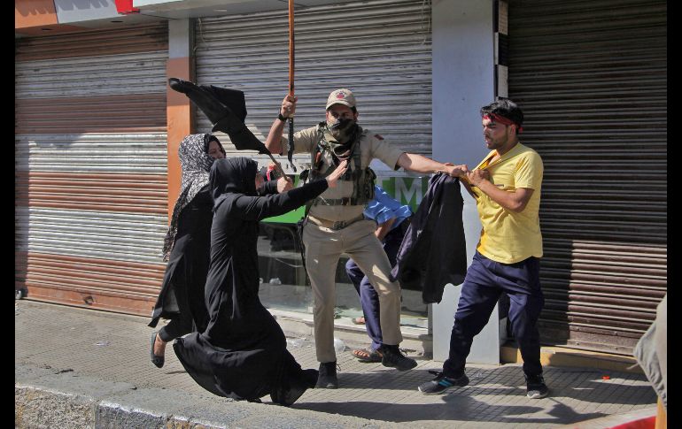 Chiítas cachemiras corren para ayudar a un joven detenido por policías durante una procesión en Srinagar, India. Autoridades dispersaron procesiones religiosas para evitar manifestaciones contra la India. AP/M. Khan