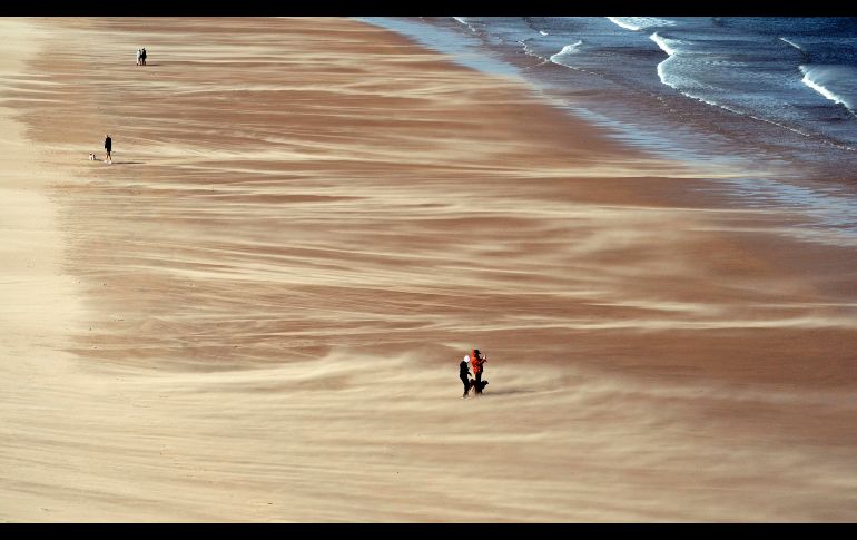 Personas caminan por la playa en Tynemouth, en la costa noreste de Inglaterra, mientras se esperan fuertes vientos en la región. AP/PA/O. Humphreys