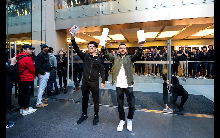 El estudiante Teddy Lee (c-d) y e Mazen Kourouche (c-i) sostienen sus nuevos iPhone en Sídney, Australia.