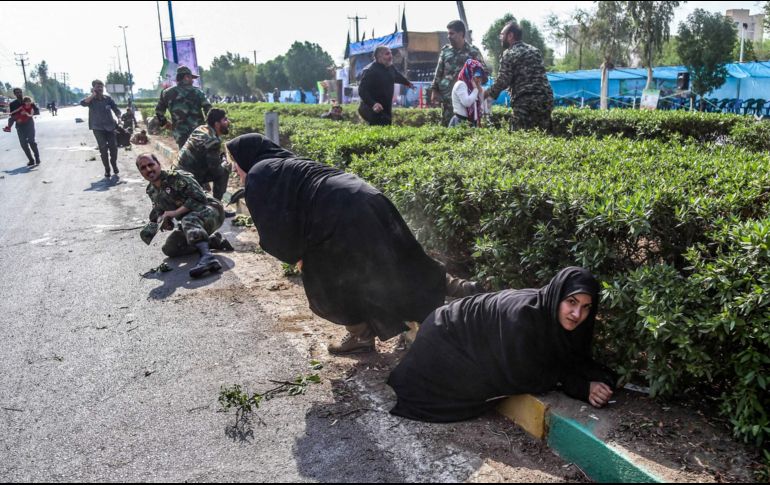 Mujeres y soldados iraníes se cubren tras el ataque en el desfile militar que dejó al menos 25 muertos. AFP /