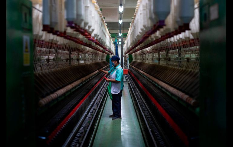 Un trabajador revisa una máquina en una fábrica textil en Pathum Thani, Tailandia. AFP/L. Suwanrumpha