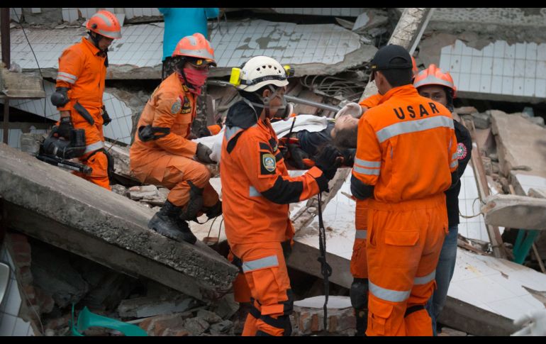Rescatistas evacuan este domingo a una mujer de un restaurante colapsado en Palu, Indonesia.