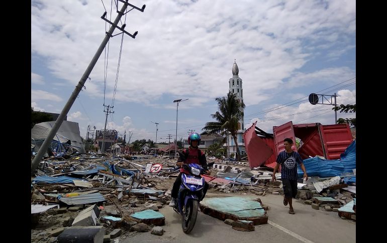 Habitantes se abren paso en una calle cubierta de escombros un día después del temblor. AFP/M. Rifki