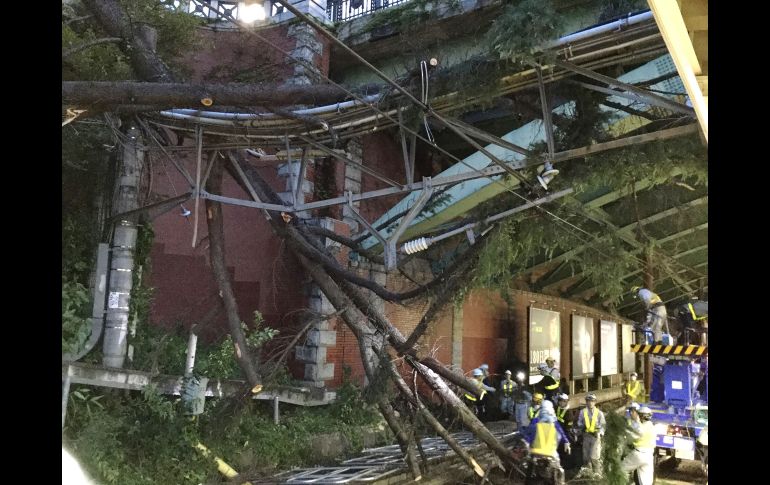 Trabajadores remueven ramas de una estación de tren en Tokio, Japón, luego del paso del tifón 