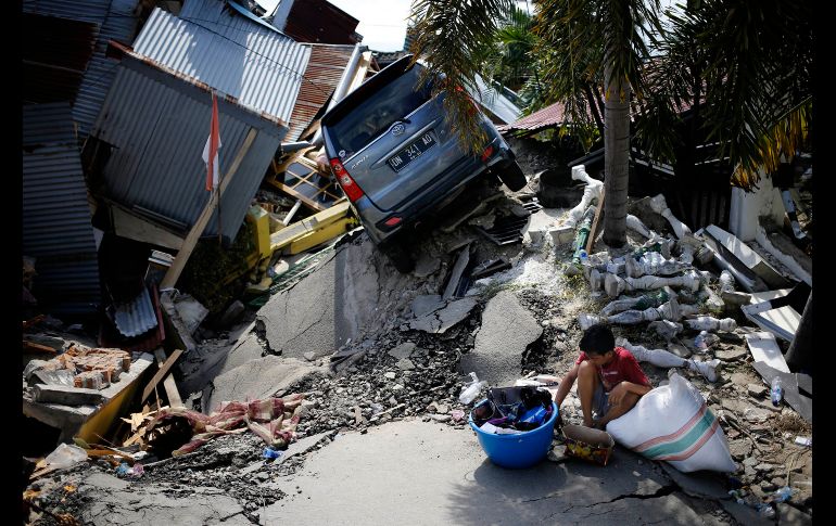 Un joven se sienta con artículos rescatados de la casa de un familiar en Palu, Indonesia, a cuatro días del temblor y tsunami que azotaron la ciudad. AP/D. Alangkara