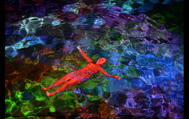 Una mujer nada en aguas iluminadas de una alberca techada en Berna, Suiza, durante un performance de la artista visual Pipilotti Rist y el Fondo Mundial para la Naturaleza, con el fin de denunciar la desaparición de corales por el calentamiento del océano. AFP/F. Coffrini