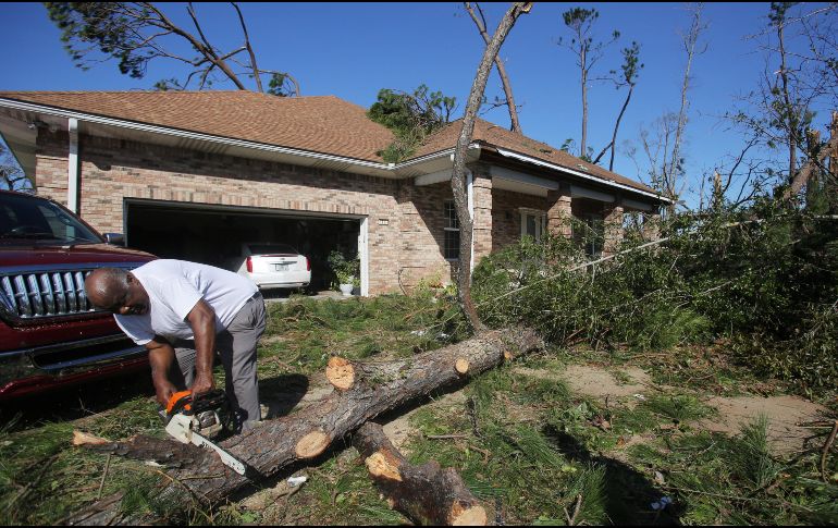 Un habitante trabaja con una motosierra para limpiar su propiedad de árboles caídos después de la llegada del huracán 