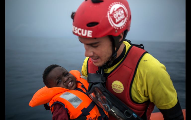 Un integrante de la organización Pro activa Open Arms sostiene a un bebé rescatado de un bote inflable que transportaba migrantes en el mar Mediterráneo, cerca de la costa española. AP/J. Fergo