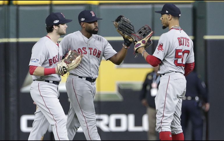 Los jugadores Andrew Benintendi (i), Jackie Bradley Jr. (c) y Mookie Betts (d) de los Medias Rojas de Boston celebran su triunfo tras vencer a los Astros de Houston. EFE/M. Wyke