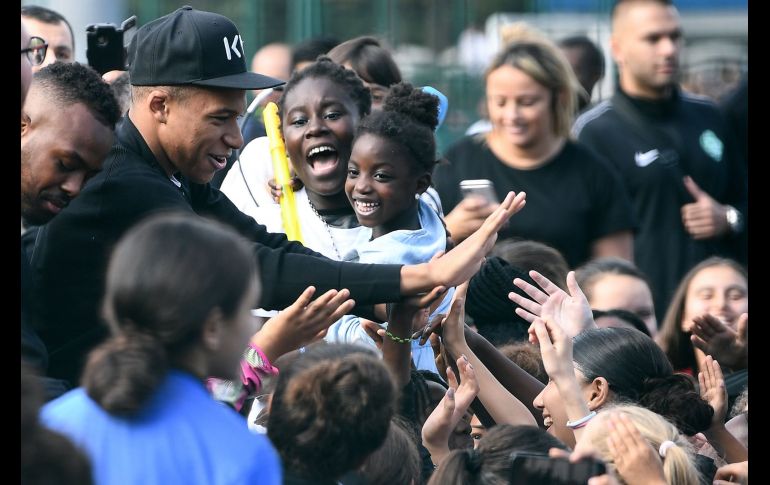 El futbolista francés  Kylian Mbappe (i) saluda a fans durante una visita al estadio  Leo Lagrange en Bondy, a las afueras París. AFP/F. Fife