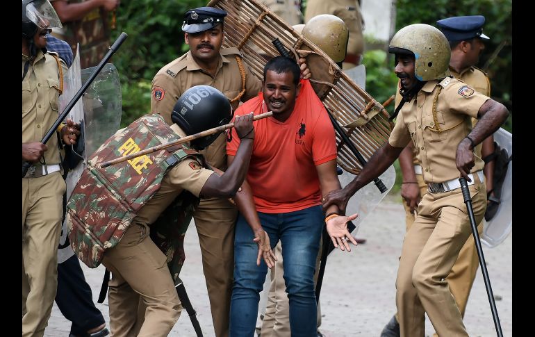 Policías golpean a un activista hindú que clama por su propia seguridad en Nilackal, India, durante protestas contra el veredicto de la Suprema Corte que quita la prohibición a la entrada de mujeres a un templo. AFP/A. Sankar