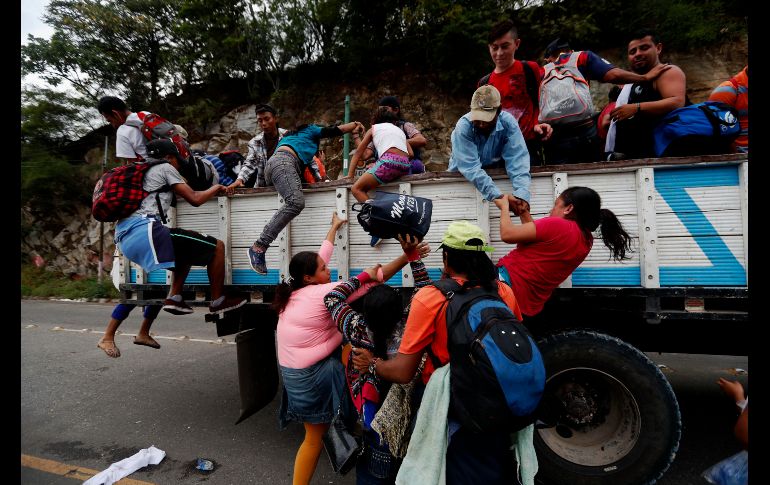 Migrantes hondureños que van en caravana hacia la frontera de México suben a camiones y aprovechan un cruce donde transita transporte pesado en el departamento de Zacapa, Guatemala. EFE/E. Biba