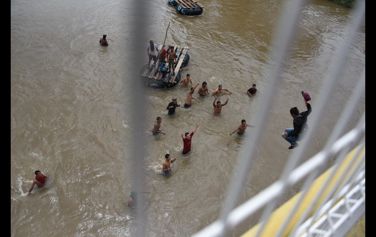 Migrantes nadan por el Suchiate tras saltar del puente fronterizo. AFP/J. Ordonez