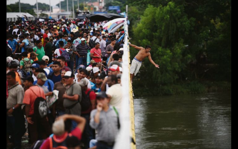 Migrantes hondureños en la frontera de México y Guatemala se tiran del puente hacia el Río Suchiate para cruzar. EFE