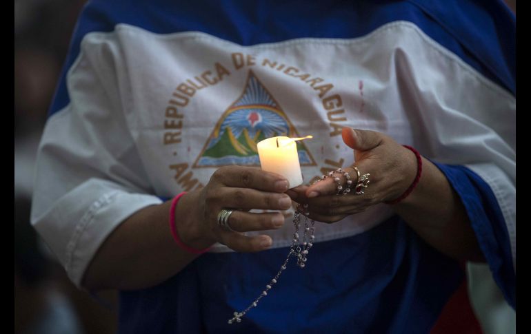 Una mujer con una bandera de Nicaragua y una vela participa de una misa para pedir por la liberación de los presos políticos por protestar contra el Gobierno del presidente Daniel Ortega, en la catedral de Managua, Nicaragua. EFE/J. Torres