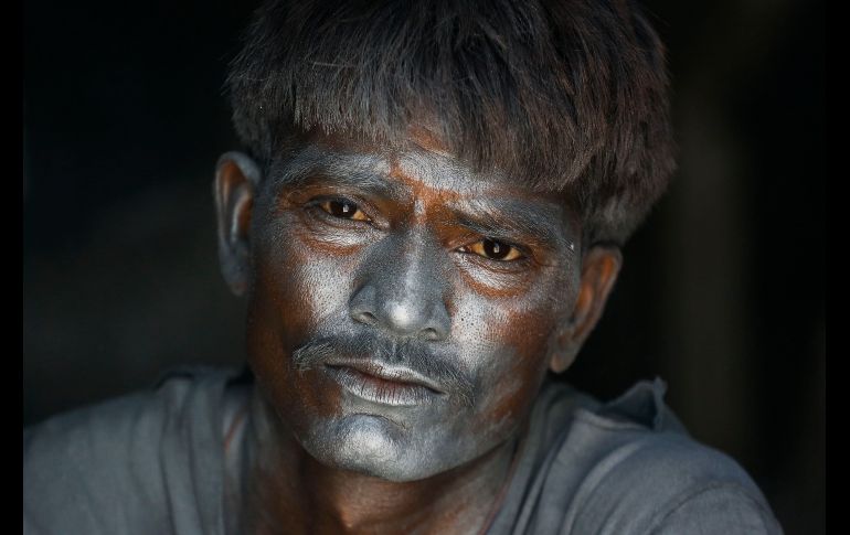 Un trabajador se llena el rostro de pólvora mientras fabrica fuegos artificiales para el festival hindú 