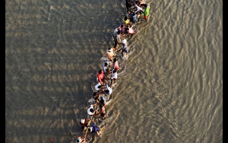 Trabajadores jalan una cuerda para un puente flotante sobre el río Ganges, como parte de los preparativos del festival 