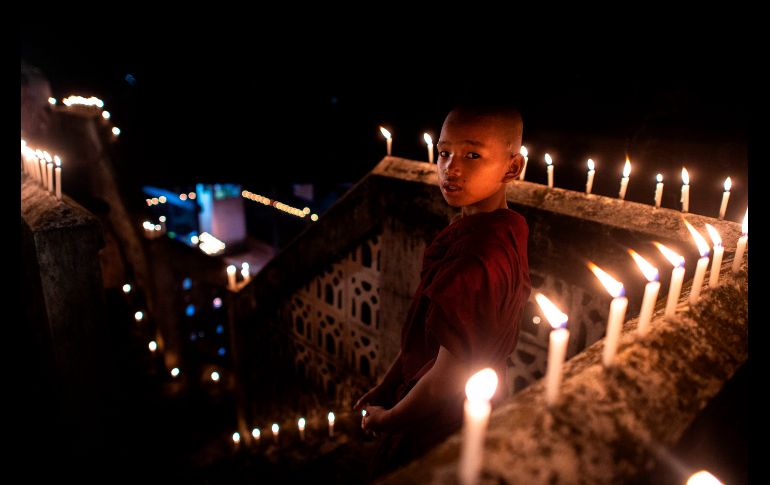 Un novicio budista enciende velas durante el festival 