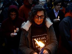 Una persona sostiene una vela durante un acto de homenaje a las víctimas. AP/M. Rourke