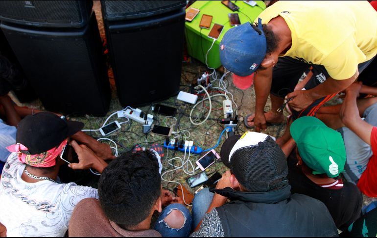 Cientos de hondureños recargan energía (para el cuerpo y para sus celulares) en Oaxaca, una de las escalas de la caravana migrante que va a Estados Unidos. NOTIMEX/F. Estrada
