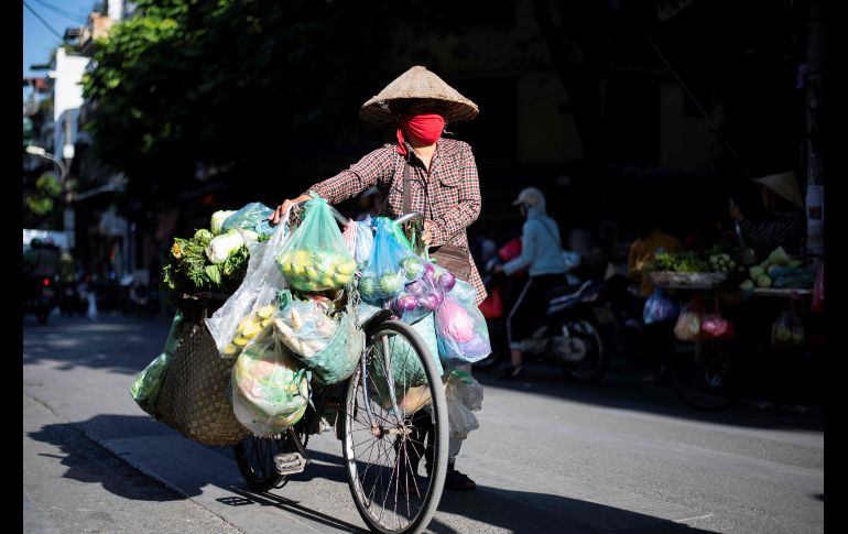 Una vendedora ambulante de vegetales recorre el mercado de Hanoi, Vietman con su bicicleta cargada de mercancía. AFP / J. Samad