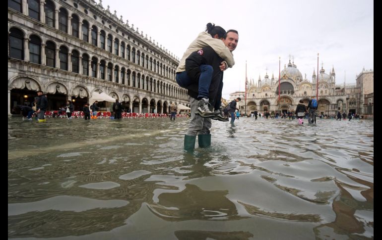 Un hombre carga a sus espaldas con su hija en la Plaza de San Marco, en Venecia, Italia, inundada como consecuencia del temporal de lluvia. EFE / A. Merola