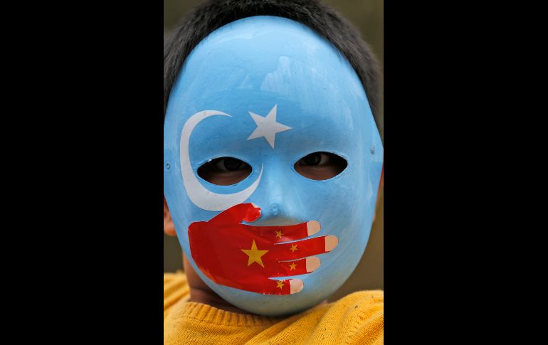 Un niño de la etnia uigur participa en una protesta en Estambul, Turquía, en contra de la presunta opresión del gobierno chino a la etnia musulmana. Su máscara lleva los colores de la bandera a la que los uigures llaman Turquestán Oriental y una mano con los colores de la bandera china. AP/L. Pitarakis
