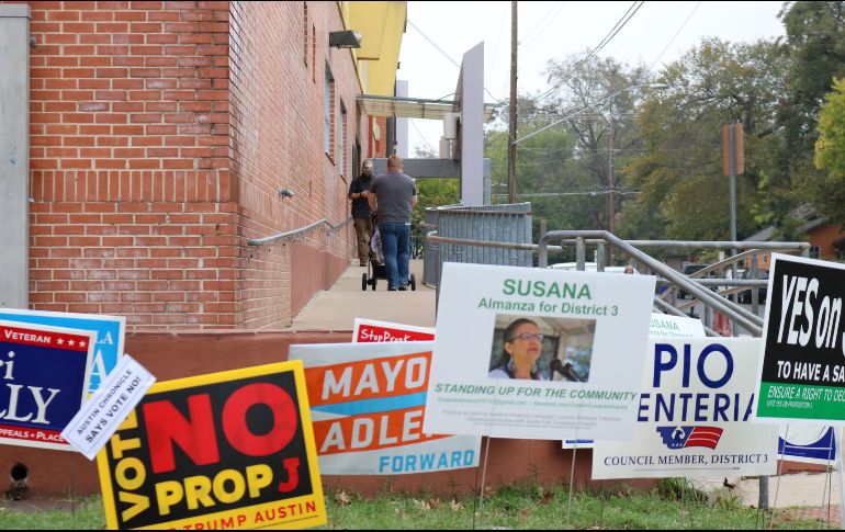 Unas personas entran a votar frente a carteles de candidatos a legislativas, a las afueras de la biblioteca pública Ruiz Branch en el sureste de Austin, Texas. EFE/J. Pascual