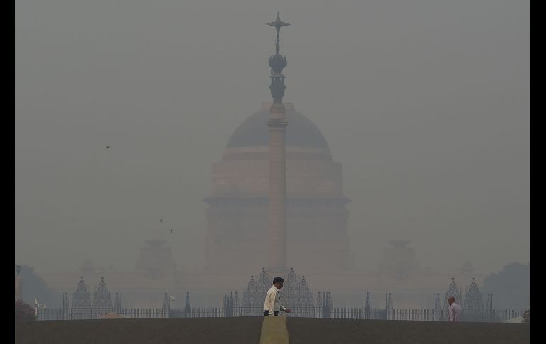 Peatones pasa cerca de la casa del presidente de la India en Nueva Delhi, en una jornada de niveles peligrosos de contaminación, tras las celebraciones con fuegos artificiales por el festival 