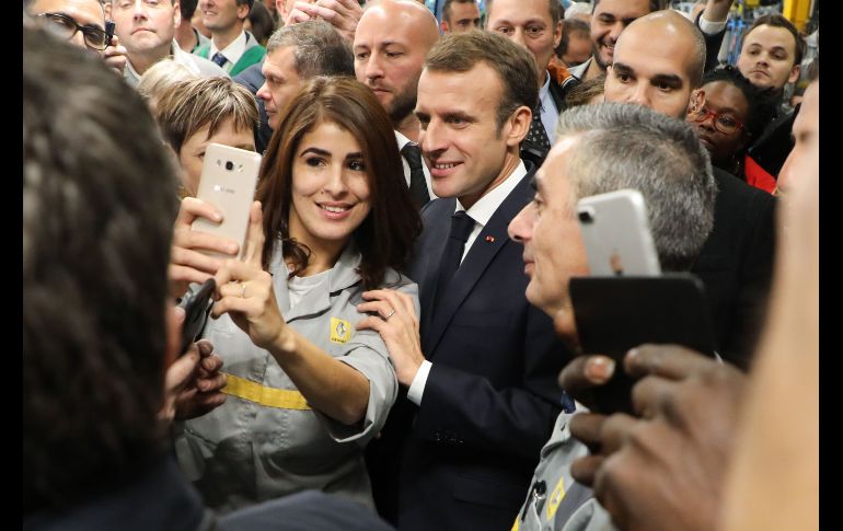 El presidente francés Emmanuel Macron (c) posa para una selfie con trabajadores de Renault, durante una visita a la fábrica de la empresa en Maubeuge, Francia. AFP/L. Marin