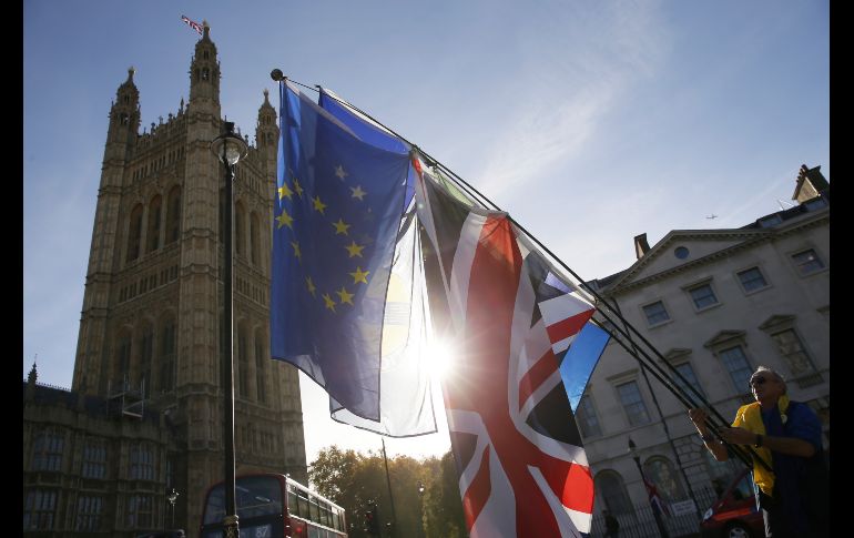 Un manifestante ondea banderas afuera del Parlamento en Londres. La primera ministra británica, Theresa May, reunió el miércoles a su dividido consejo de ministros para intentar que apruebe el controvertido acuerdo de 